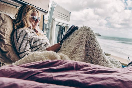 Frau chillt in Sunlight Van und ist mit einer Decke zugedeckt